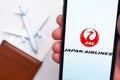 Japan Airlines Airline application is displayed on the smartphone screen. There is a blurry plane, passport and boarding