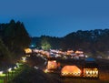 Night scenery of a glamping farm cottage resort with tents lit by lanterns in the forest.