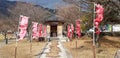 E walkway entrance to the shrine with many decorative flags and Autumn tree background.