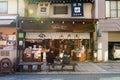 Young people, lovers, or friends eating food on bench in front of the snack shop and souvenirs on street food at Takayama, Japan Royalty Free Stock Photo