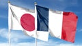 Japan and France flags against cloudy sky. Royalty Free Stock Photo