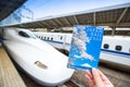 Japan Rail Pass Image, hand hold JR Pass ticket in front of Shinkansen at Tokyo Station. JR Pass is a rail pass coupon