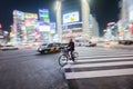 A man rides a bicycle passing the busy street of Shibuya crossing