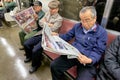 Japan. Tokyo. Passengers on the subway, reading the newspaper
