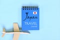 Japan travel journal diary written on blue notepad with flag and wooden airplane. Minimalist flat lay composition. Royalty Free Stock Photo