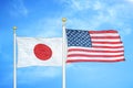 Japan and United States two flags on flagpoles and blue cloudy sky Royalty Free Stock Photo