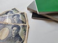Japanese banknotes of 1000 yen and stacked books on white background