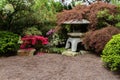 Japanese botanical garden. Stone lantern; trees and flowering shrubs. Gravel in foreground. Royalty Free Stock Photo