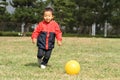 Japanese boy kicking a yellow ball Royalty Free Stock Photo