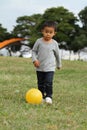 Japanese boy kicking a yellow ball Royalty Free Stock Photo