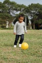 Japanese boy kicking a yellow ball Royalty Free Stock Photo