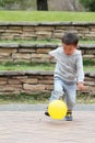 Japanese boy kicking a yellow ball Royalty Free Stock Photo