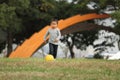 Japanese boy kicking a yellow ball on the grass Royalty Free Stock Photo