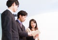 Japanese business woman and business men talking at desk, looking at documents on tablet device