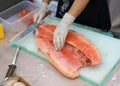 Japanese chef in restaurant slicing raw fish for salmon sushi. Chef preparing a fresh salmon on a cutting board Royalty Free Stock Photo