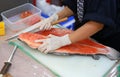 Japanese chef in restaurant slicing raw fish for salmon sushi. Chef preparing a fresh salmon on a cutting board Royalty Free Stock Photo