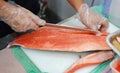 Japanese chef in restaurant slicing raw fish for salmon sushi. Chef preparing a fresh salmon on a cutting board Royalty Free Stock Photo
