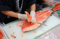 Japanese chef slicing raw fish for salmon sushi. Chef preparing a fresh salmon on a cutting board