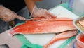 Japanese chef slicing raw fish for salmon sushi. Chef preparing a fresh salmon on a cutting board