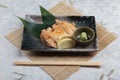 Japanese chicken grilled with sea salt served with sliced lemon and wasabi in stone rectangle plate with chopstick on makisu.