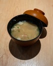 Japanese classic miso soup in a black bowl on wooden table.