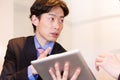 Japanese consultant talking with client, showing data with tablet device