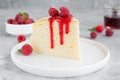 Japanese cotton cheesecake on a stand on a gray concrete background with fresh raspberries and powdered sugar on top.