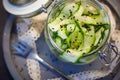 Japanese cucumber salad with black and white sesame seeds in mason jar with lid on concrete round tray, grey background decorated