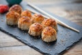 Japanese cuisine. Baked sushi with crab meat and cheese on a stone slab in a dark wood background Royalty Free Stock Photo