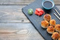 Japanese cuisine. Baked sushi with crab meat and cheese on a stone slab in a dark wood background. Top view with copy space Royalty Free Stock Photo