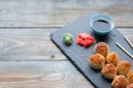 Japanese cuisine. Baked sushi with crab meat and cheese on a stone slab in a dark wood background. Top view with copy space Royalty Free Stock Photo