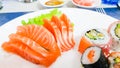 Japanese cuisine, Fresh Salmon sashimi and sushi roll with green salad on white plate  on white background Royalty Free Stock Photo