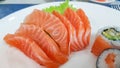 Japanese cuisine, Fresh Salmon sashimi and sushi roll with green salad on white plate  on white background Royalty Free Stock Photo