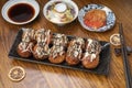 Japanese cuisine Takoyaki octopus balls with takoyaki sauce on wooden table, Traditional Japanese food. Royalty Free Stock Photo