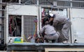 Japanese engineers fixing an air conditioning unit on a Tokyo street, Japan