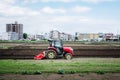 Japanese farmer plowing a field using a red tractor in spring Royalty Free Stock Photo