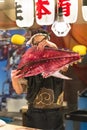 Japanese fishmonger holding a fish after a tuna cutting show in a sushi restaurant.