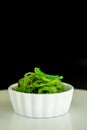 Japanese food concept. Fresh seaweed salad with sesame seeds in white bowl on black background Royalty Free Stock Photo