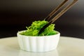 Japanese food concept. Fresh seaweed salad with sesame seeds in white bowl with chopstick on black background Royalty Free Stock Photo