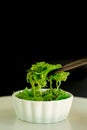 Japanese food concept. Fresh seaweed salad with sesame seeds in white bowl with chopstick on black background Royalty Free Stock Photo