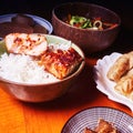 Japanese food in small bowls with rice, salmon, gyoza and eggplant