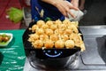 a woman cooking Takoyaki or a ball-shaped Japanese snack on a black pan