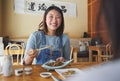 Japanese, food and woman at a restaurant eating for dinner or lunch meal using chopsticks and feeling happy with smile Royalty Free Stock Photo