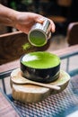 Japanese fusion dessert: Hand poured Green Tea Powder on white pudding. Serve in a black ceramic bowl on timber with wooden spoon