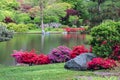 Missouri Botanical Garden. Lake with reflection of trees and plants. Red, pink flowers on shore. Green grass and rocks in foregrou Royalty Free Stock Photo