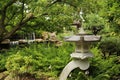 A Japanese garden with a stone lantern, Maple tree, shrubs, ferns and a stone waterfall in Wisconsin