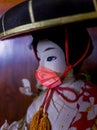 Japanese geisha doll wearing a reddish chinstrap Royalty Free Stock Photo