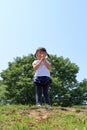 Japanese girl blowing dandelion seeds under the blue sky Royalty Free Stock Photo