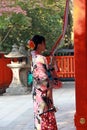 Japanese girl in Kimono dress stand and catch fabric rope to ringing the bell for bless at Fushimi Inari Shrine. Royalty Free Stock Photo