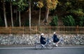 Japanese girl students riding bicycles on peaceful street with green treee background in Okayama